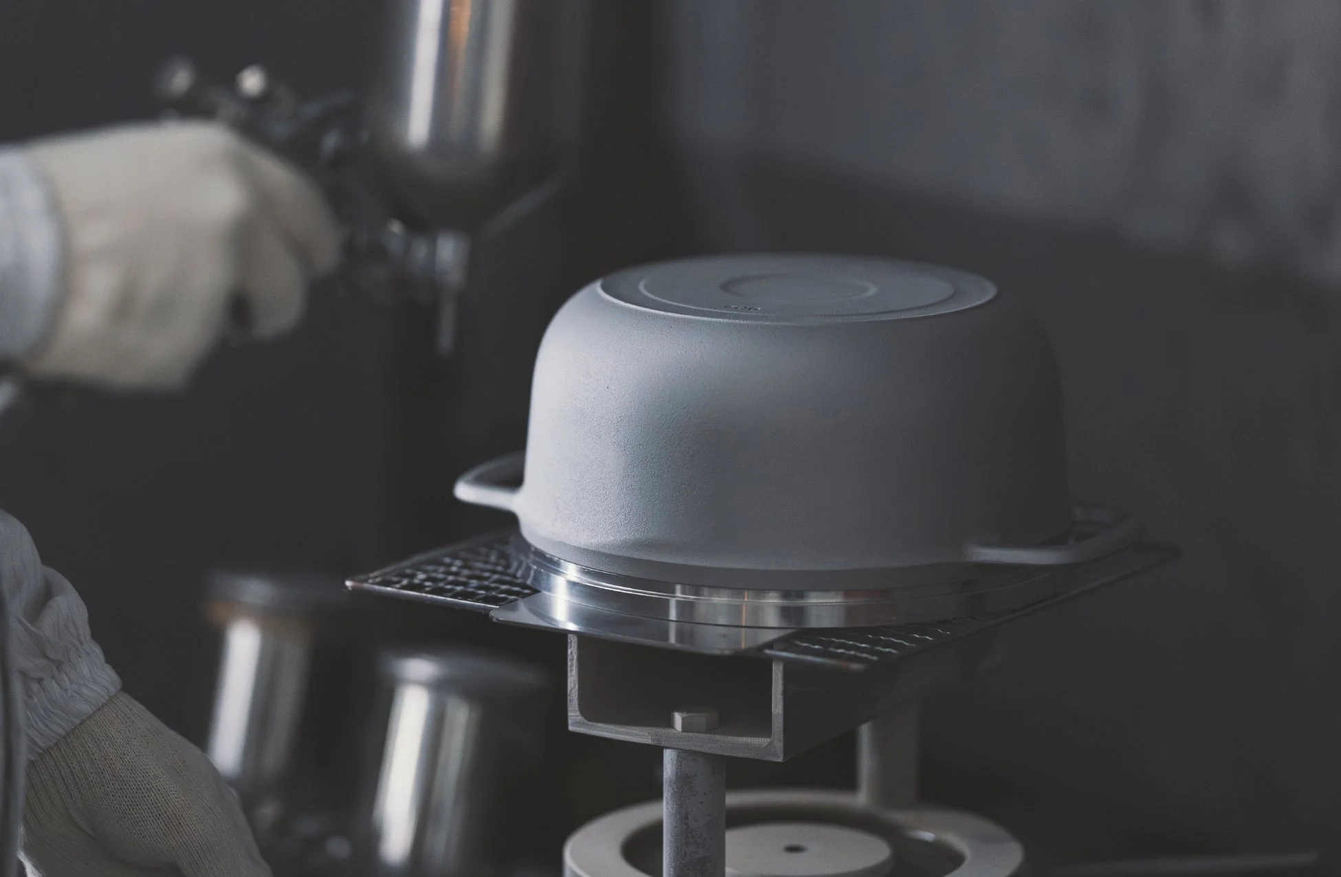 作業員がスプレーガンを使って鍋の底に塗装