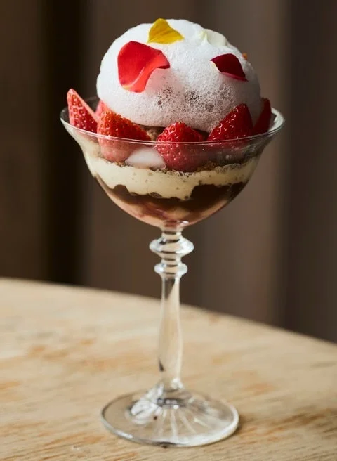 泡とバラの花びらで飾られた美しいイチゴのパフェ