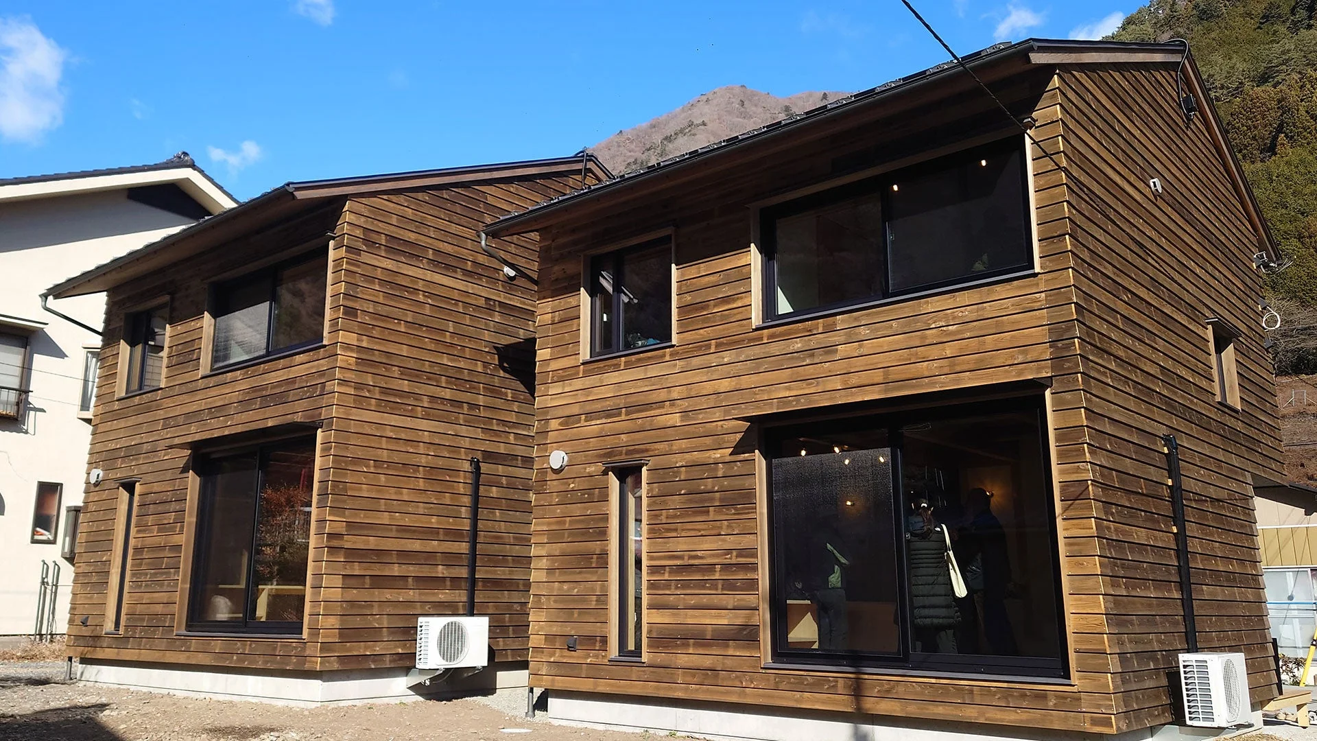 木材の外壁が特徴的なモダンなデザインの住宅が2棟並ぶ風景