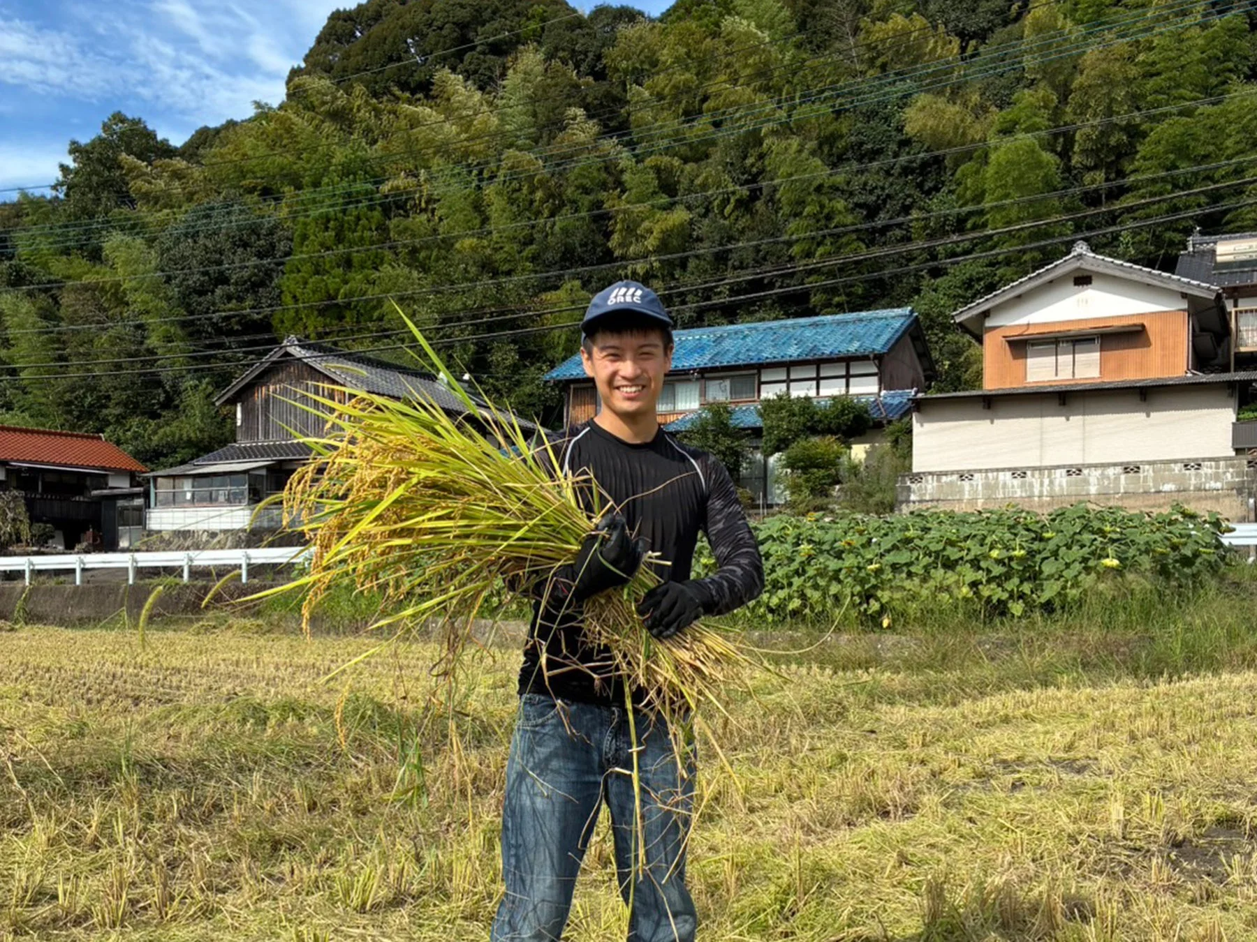 稲束を抱える男性