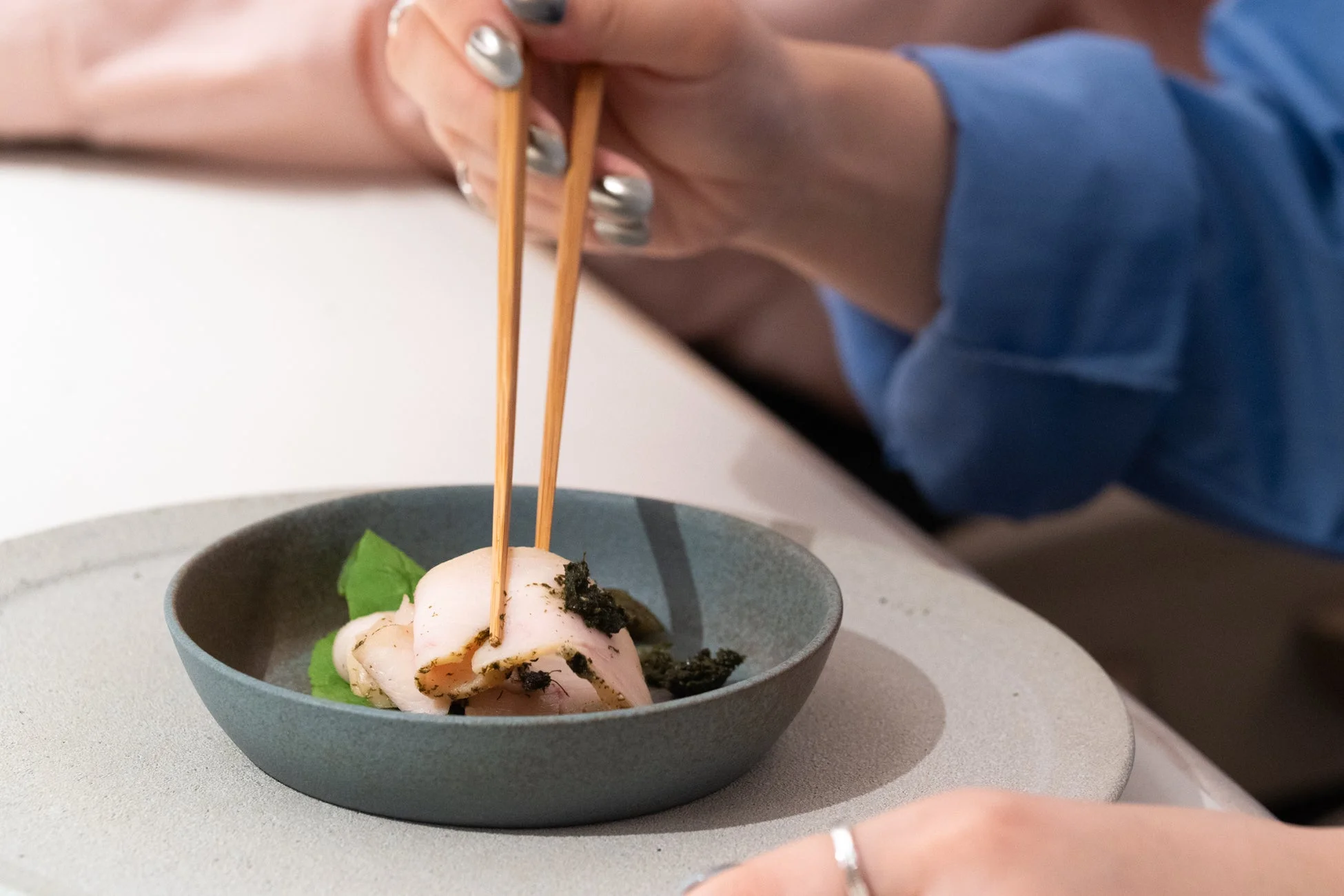 箸で小さな器に入った前菜をつまんでいる様子