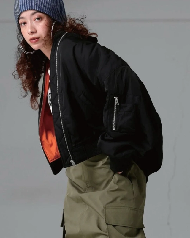 青いニット帽と黒いMA-1ジャケット、カーゴパンツを着用した女性のポートレート