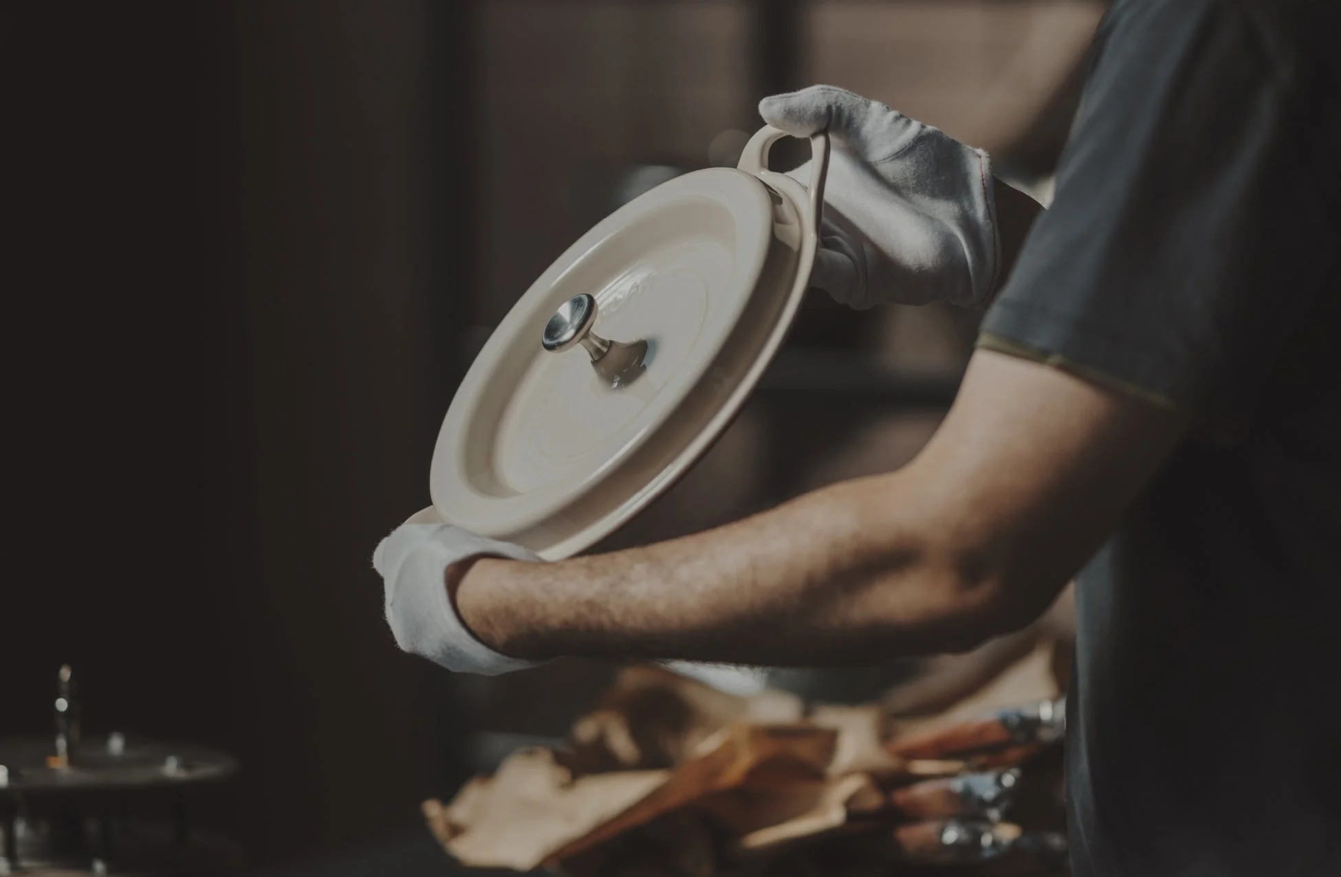 白い手袋をはめた人物が鍋蓋を持つ