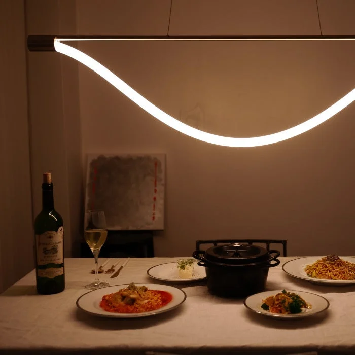 モダンな照明の下で、ワインと複数の料理が並べられた食卓の様子