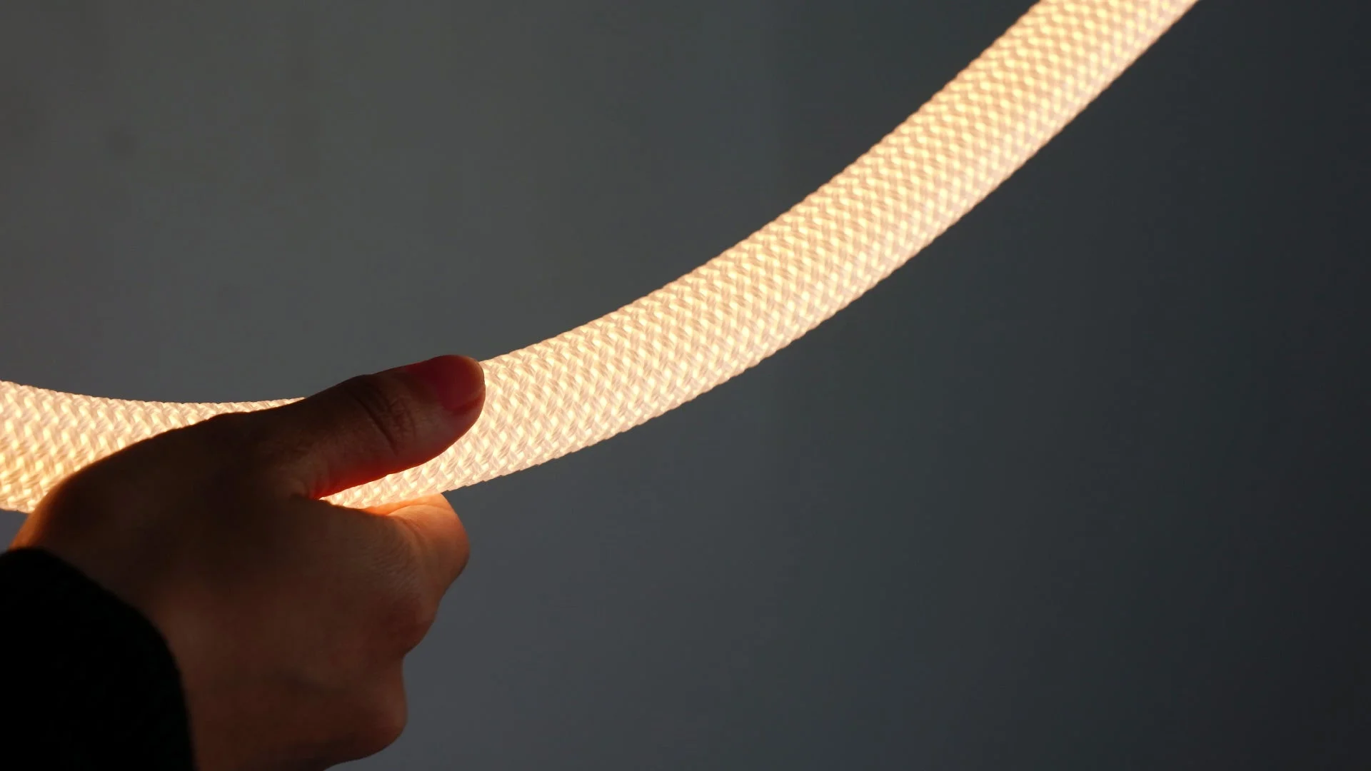 手が発光する編み込み状のロープライトを持っている様子