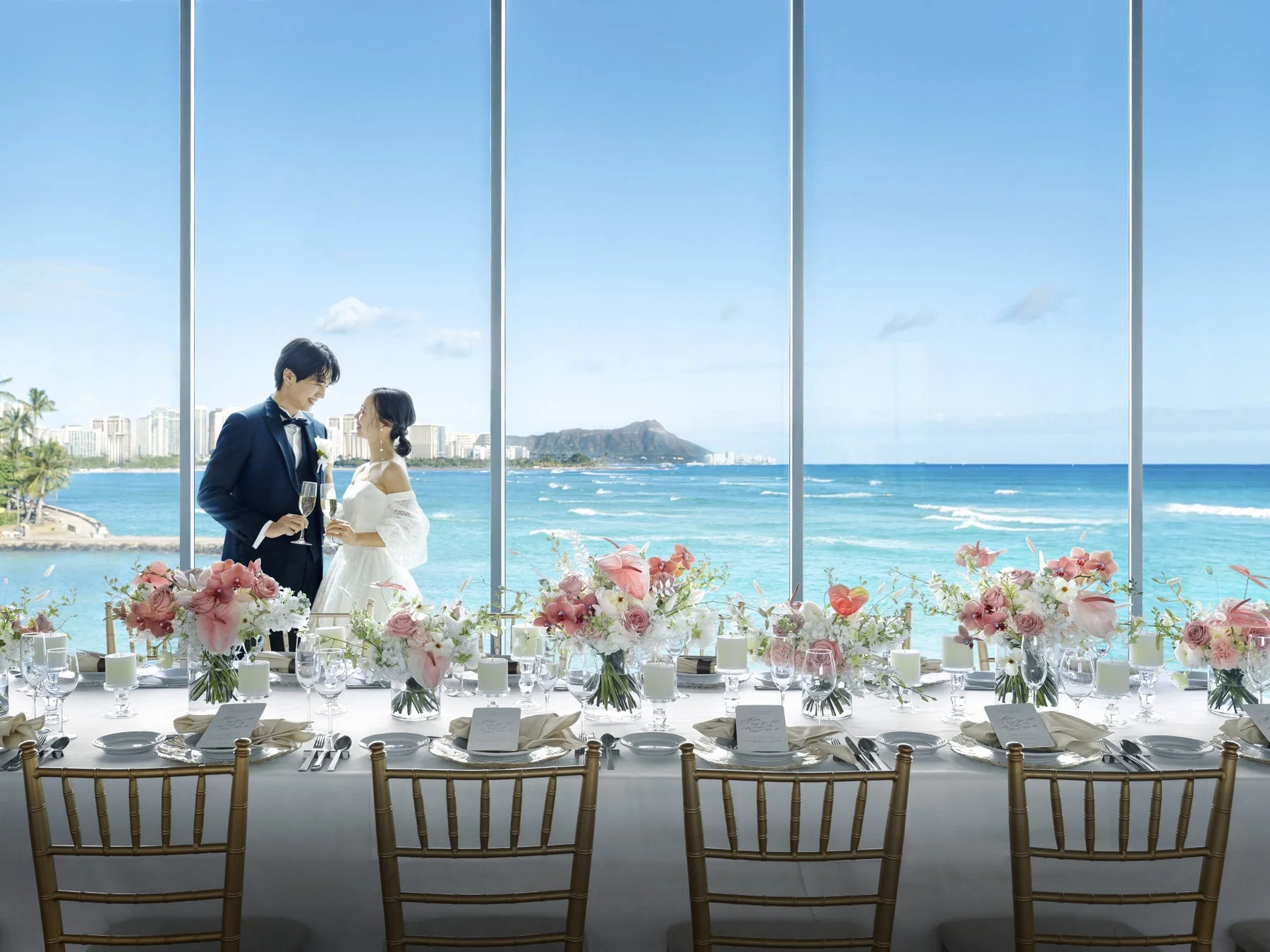 ハワイのオーシャンビューが広がる会場で、新郎新婦がシャンパングラスを片手に微笑み合う結婚式の様子です。