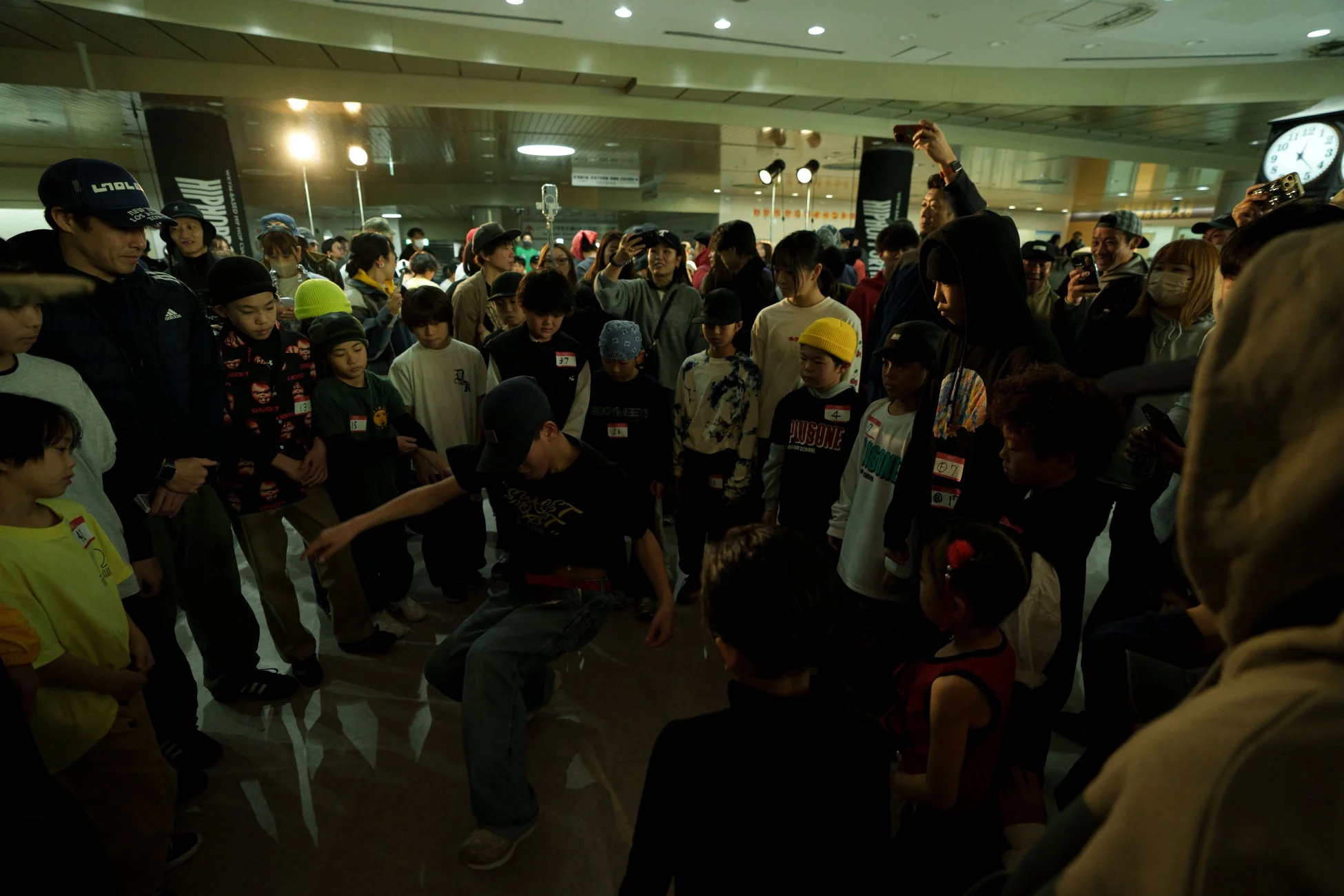 ヒップホップイベントで、多くの観客が見守る中、一人の若者がダンスを披露している