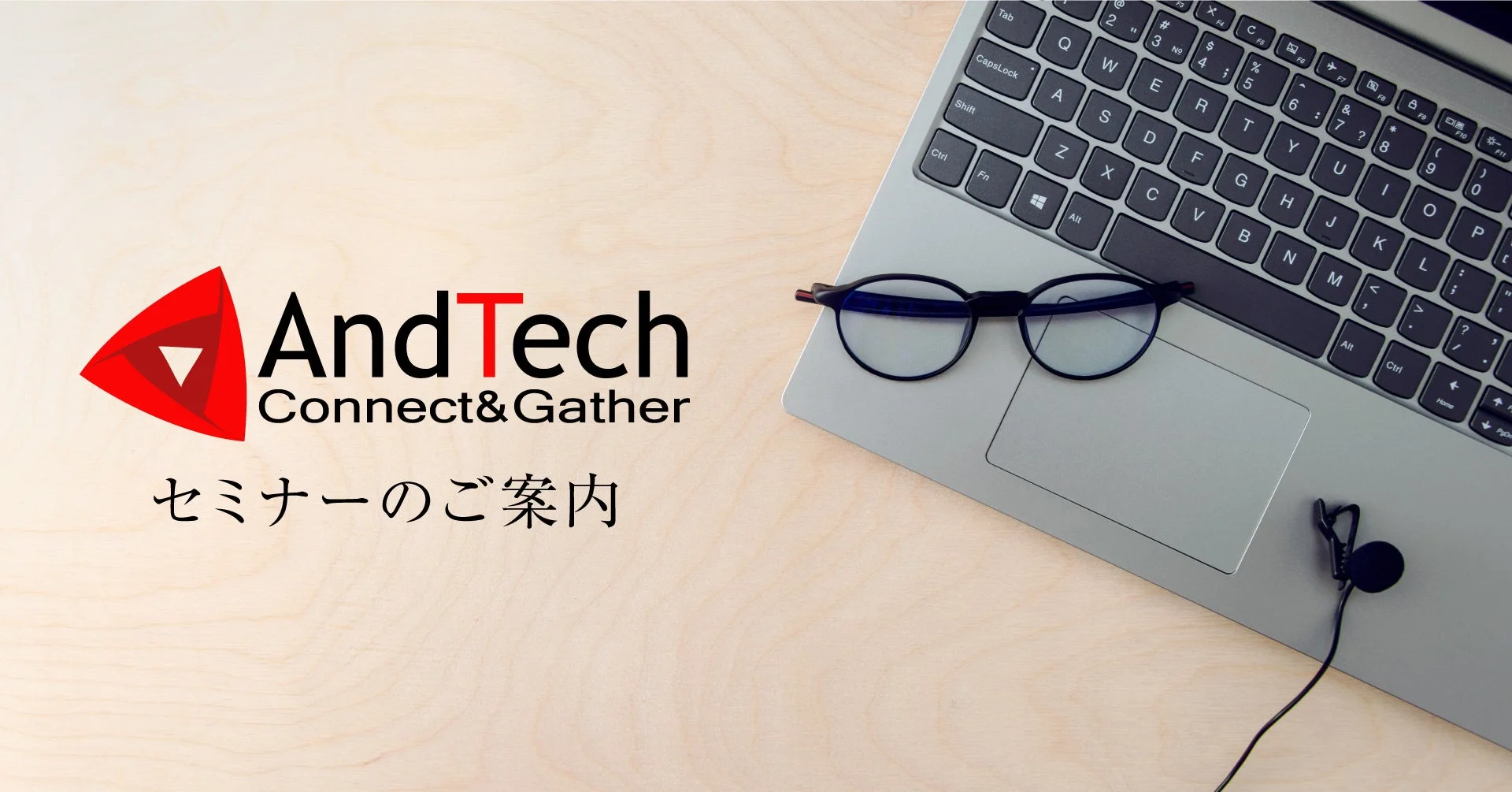 AndTech Connect&Gatherのロゴと「セミナーのご案内」の文字。木目のテーブルにノートパソコン、メガネ、ピンマイクが置かれている。