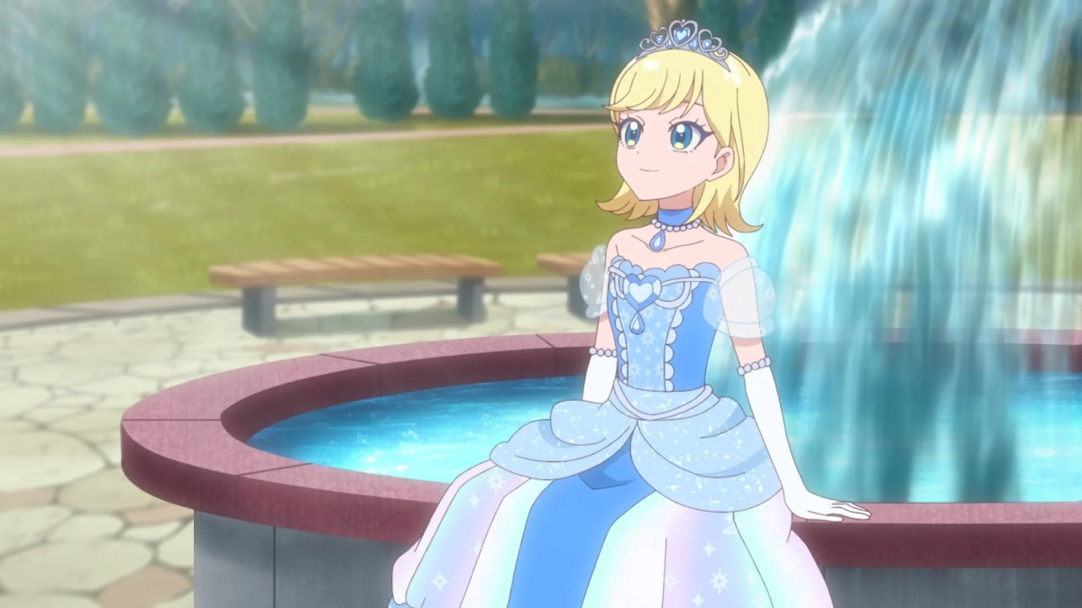 金髪の少女が水色のプリンセスドレスを着て、公園の噴水の縁に座っているアニメーション画像です。
