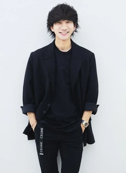 黒い服を着て笑顔で立っている若い男性のポートレート。カジュアルな服装で、パンツには「CELINE」のロゴが見えます。